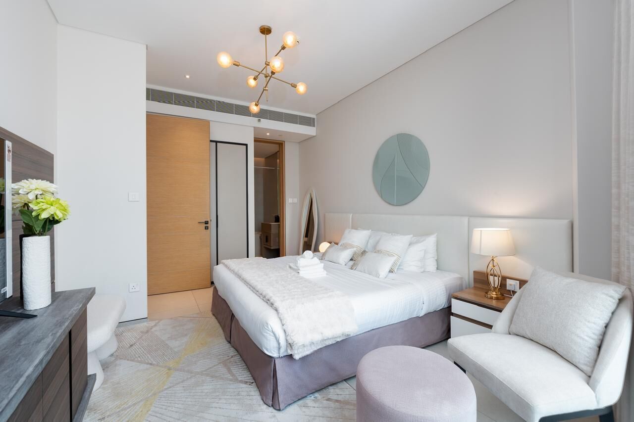 Une chambre d’hôtel moderne dotée d’un grand lit, de tables de chevet, d’un coin salon et d’un élément décoratif mural.