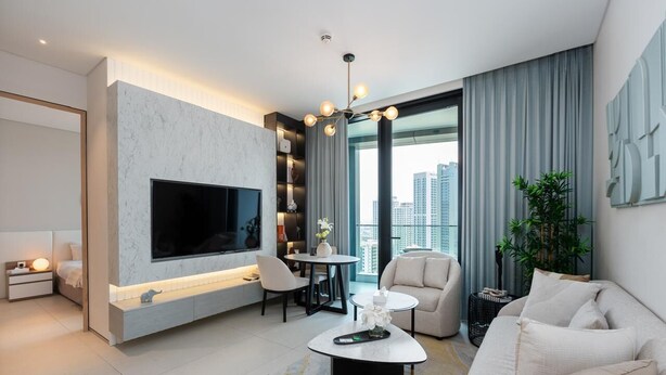 A modern living room with a flat-screen TV, a round coffee table, and a sofa.