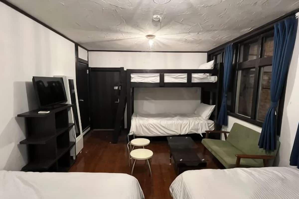 A room with bunk beds, a TV, a desk, and a window with curtains.