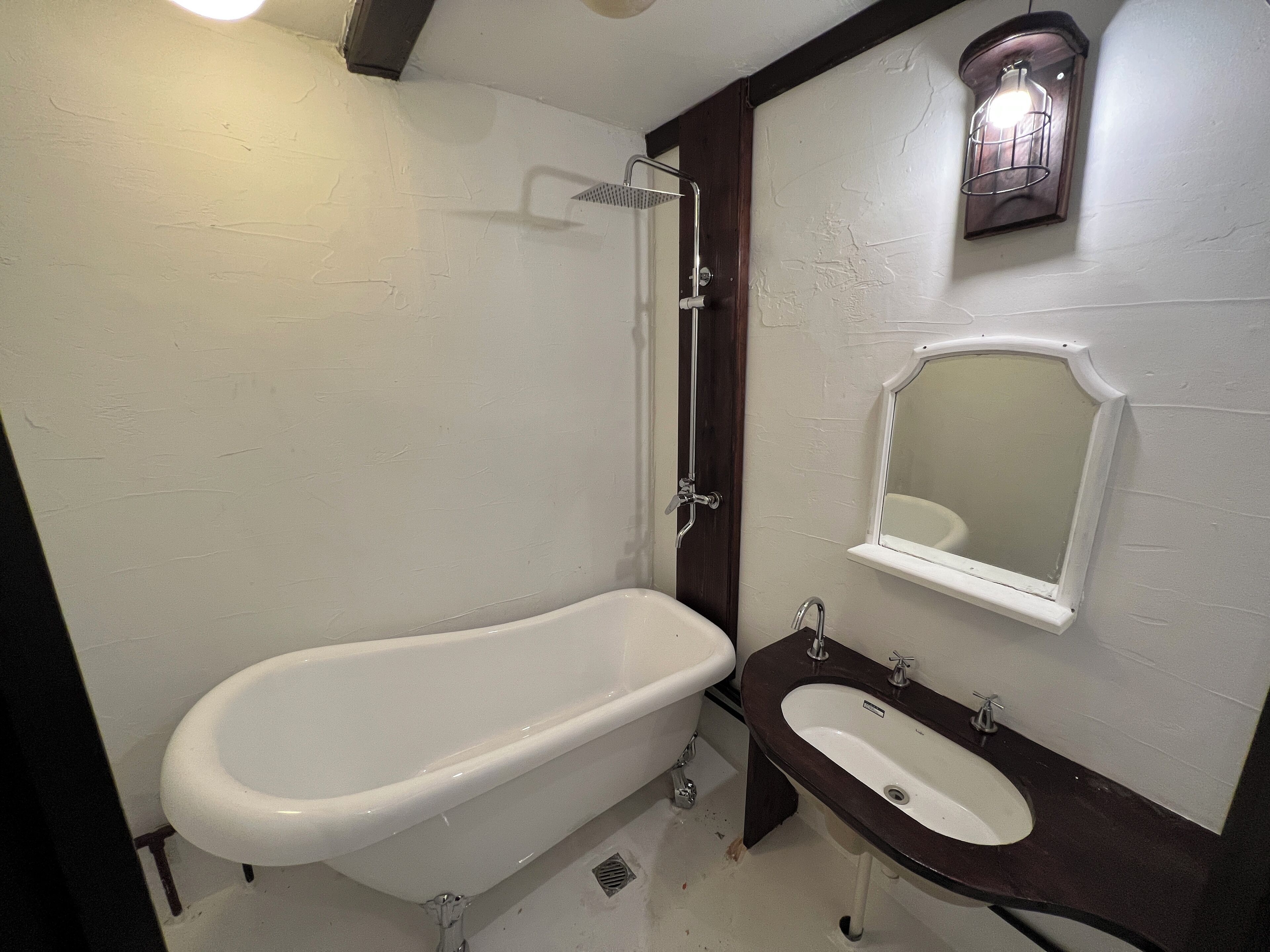 A bathroom with a freestanding bathtub, a pedestal sink, and a wall-mounted mirror.