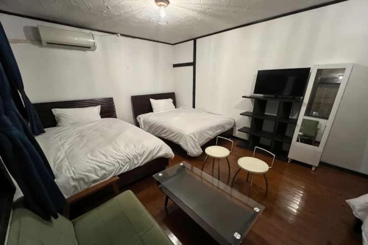 A hotel room with two beds, a TV, a desk, and a wardrobe.