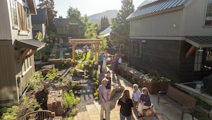 A courtyard with stone pathways, a pergola, and a group of people.