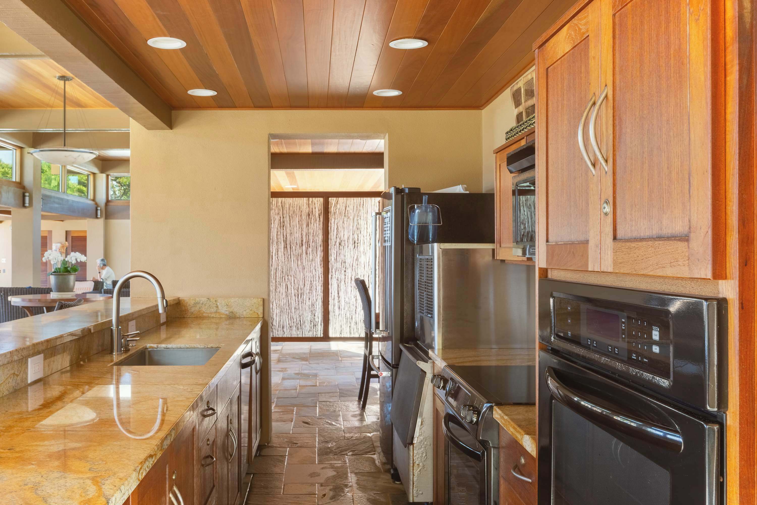 Una cocina moderna con encimera de piedra, electrodomésticos de acero inoxidable y muebles de madera.