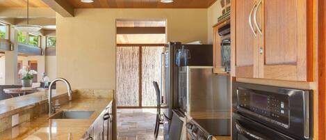 Una cocina moderna con encimera de piedra, electrodomésticos de acero inoxidable y muebles de madera.