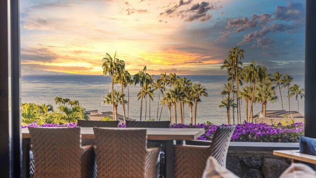 A view from a room with a table and chairs facing a sunset over the ocean, with palm trees in the foreground. - Wailea Elua condo - Ocean Views | Gym | Pickleball (Wailea-Makena)