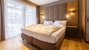 A modern bedroom with a large bed, wooden headboard, and two bedside lamps.