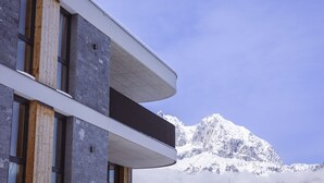 A modern building with a balcony overlooking a snow-covered mountain. - Lovely Apartment Near ski Area (Oberndorf in Tirol)