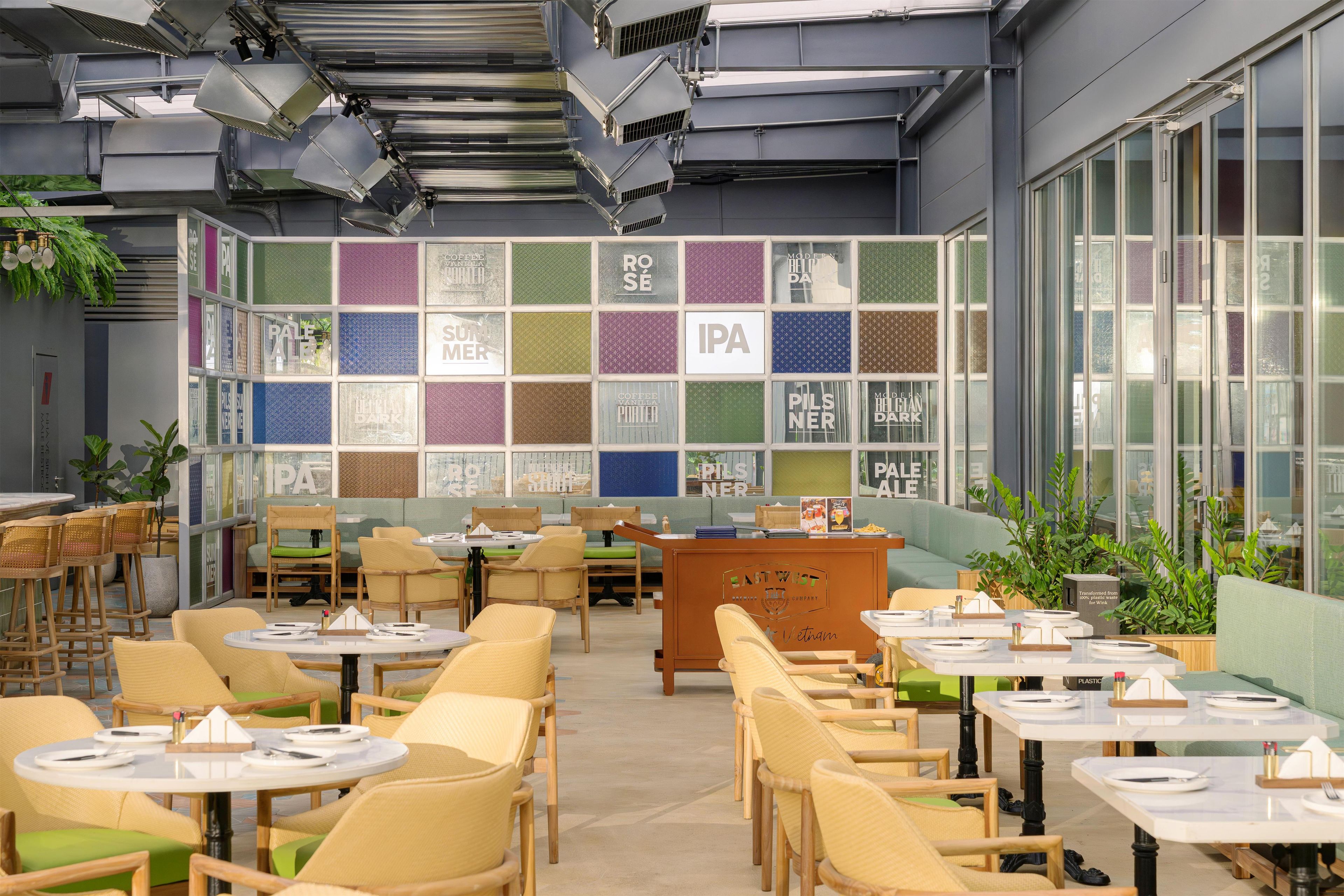 A modern cafe interior with multiple seating areas, a display wall with beverage options, and a clean, contemporary design.