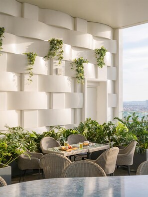 Een stijlvol terras met rieten meubels en uitzicht op de stad.