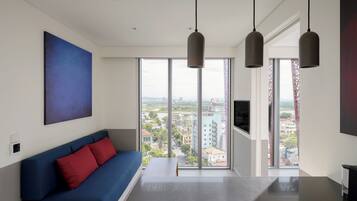 A modern living room with a blue sofa, a large window with a city view, and pendant lighting.