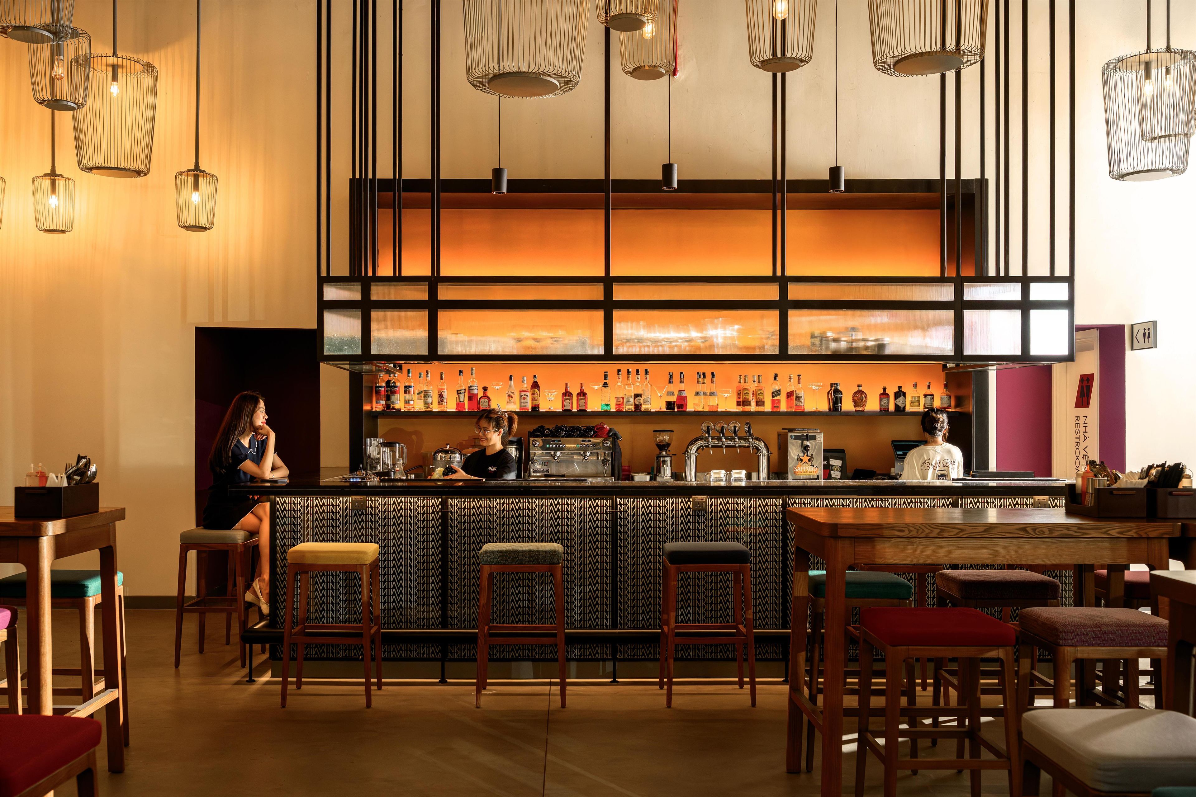 A bar area with a counter, stools, and a bartender.