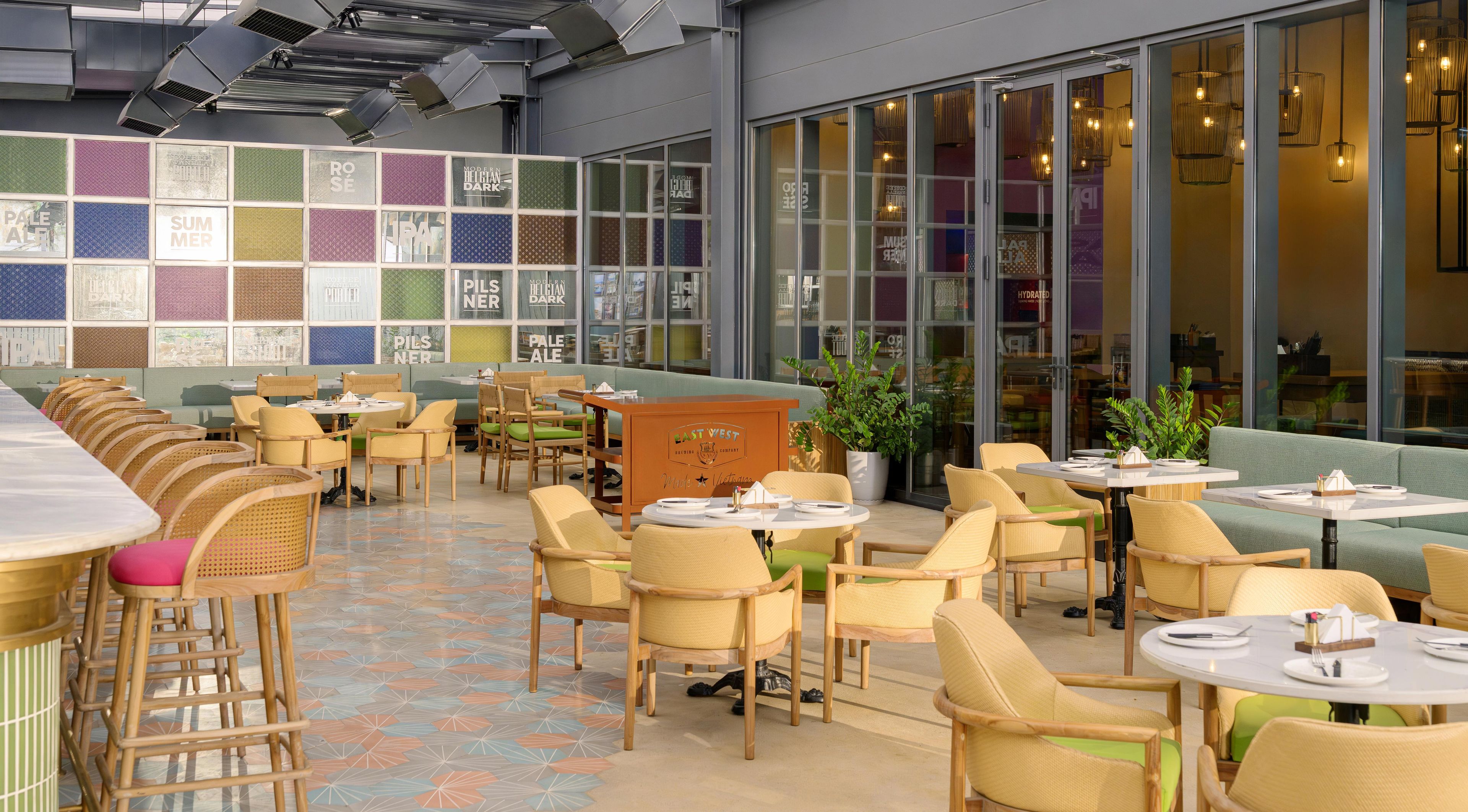 Un restaurant doté d’un long comptoir, de plusieurs espaces pour s’asseoir et d’un mur décoré de motifs colorés.