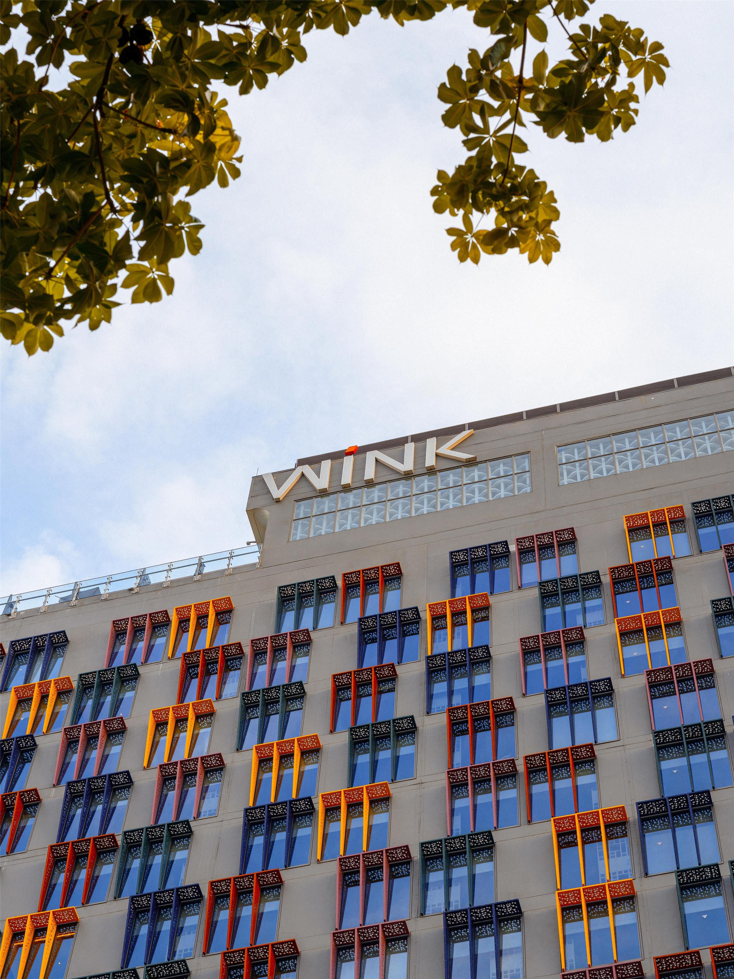 Un edificio moderno con un llamativo letrero que dice 'WINK' en la parte superior.