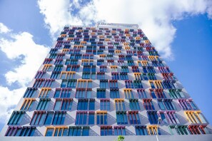 A high-rise building with a grid of windows and balconies, featuring a modern architectural design. - Wink Hai Phong Centre, Unscripted by Hyatt - 24 Hours stay (Hai Phong)