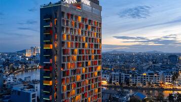 Un hotel moderno de gran altura con múltiples pisos, un llamativo letrero con la palabra 'WINK' en la parte superior y vistas de la ciudad circundante.