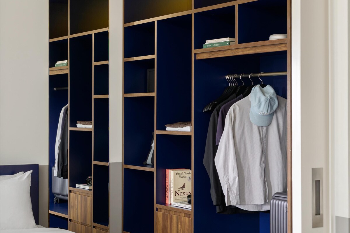 Une chambre à coucher avec un lit, une armoire dotée de plusieurs étagères et un miroir.