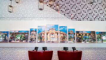 Un área de recepción con una pared decorada, varias obras de arte enmarcadas y dos zonas de estar rojas.