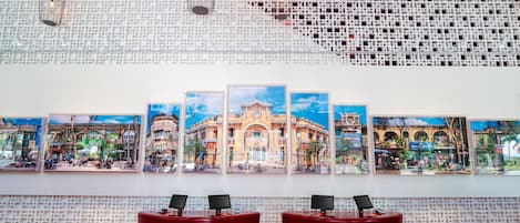 A reception area with a patterned wall, multiple framed artworks, and two red seating areas.