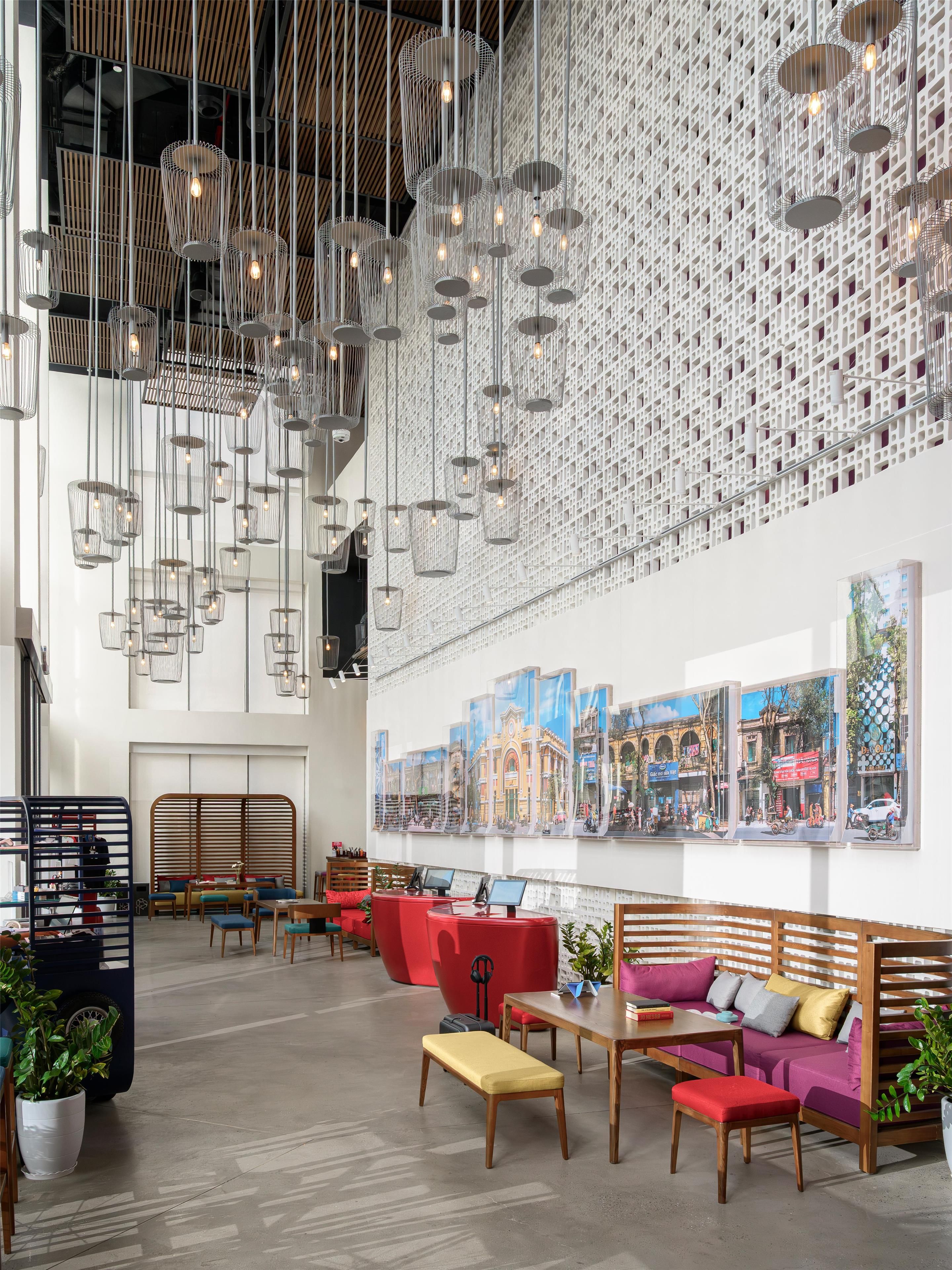 A spacious lobby with hanging pendant lights, a large wall mural, and comfortable seating areas.