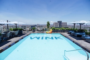 A rooftop pool with the word 'WINK' on the water, surrounded by outdoor seating and umbrellas, overlooking a cityscape. - Wink Hai Phong Centre, Unscripted by Hyatt - 24 Hours stay (Hai Phong)