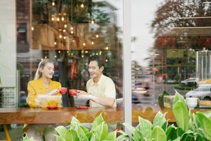 Two people sitting at a table inside a cafe with a view of the street outside.