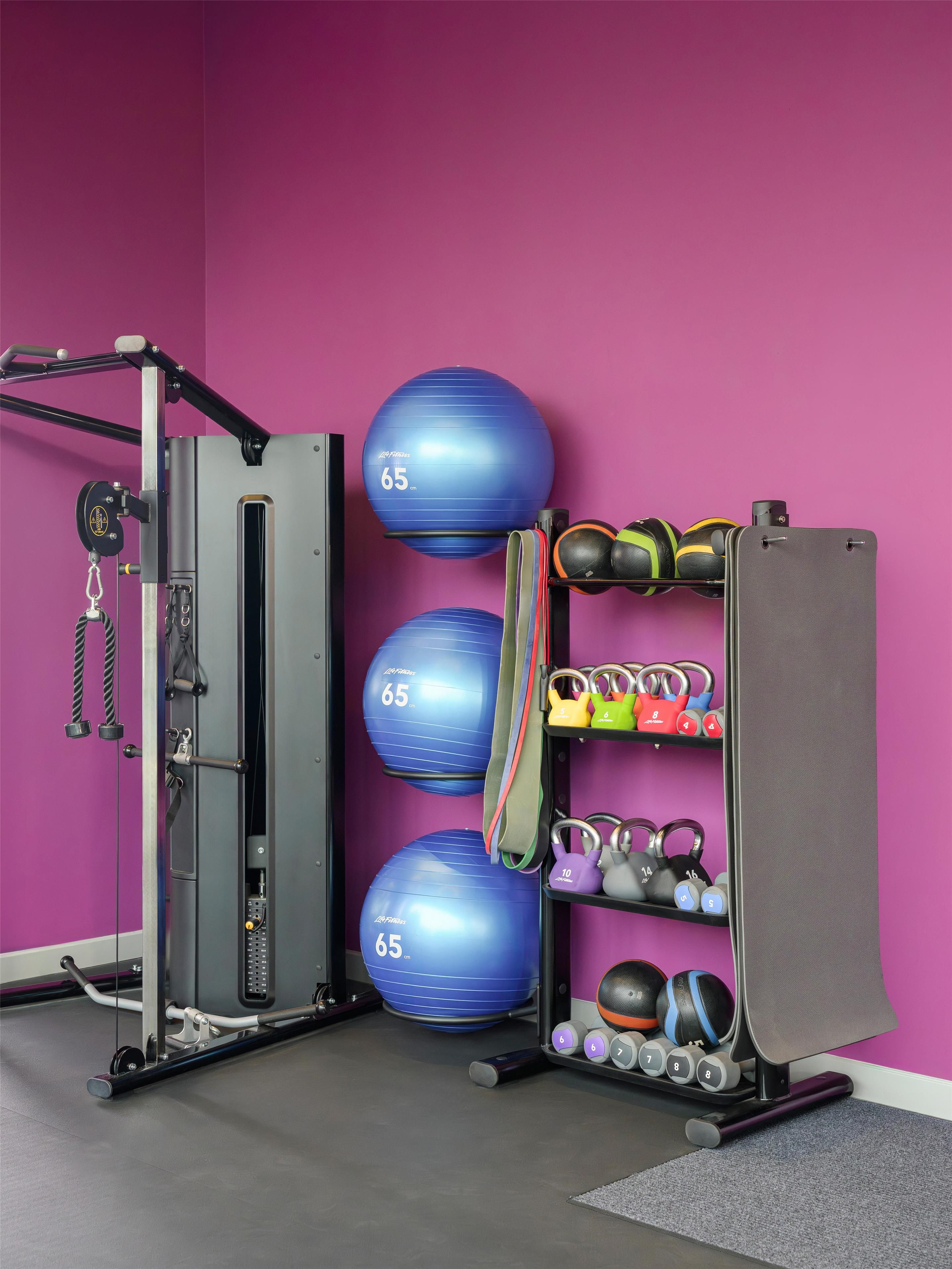 A gym with exercise equipment, including a weight machine, medicine balls, and dumbbells.