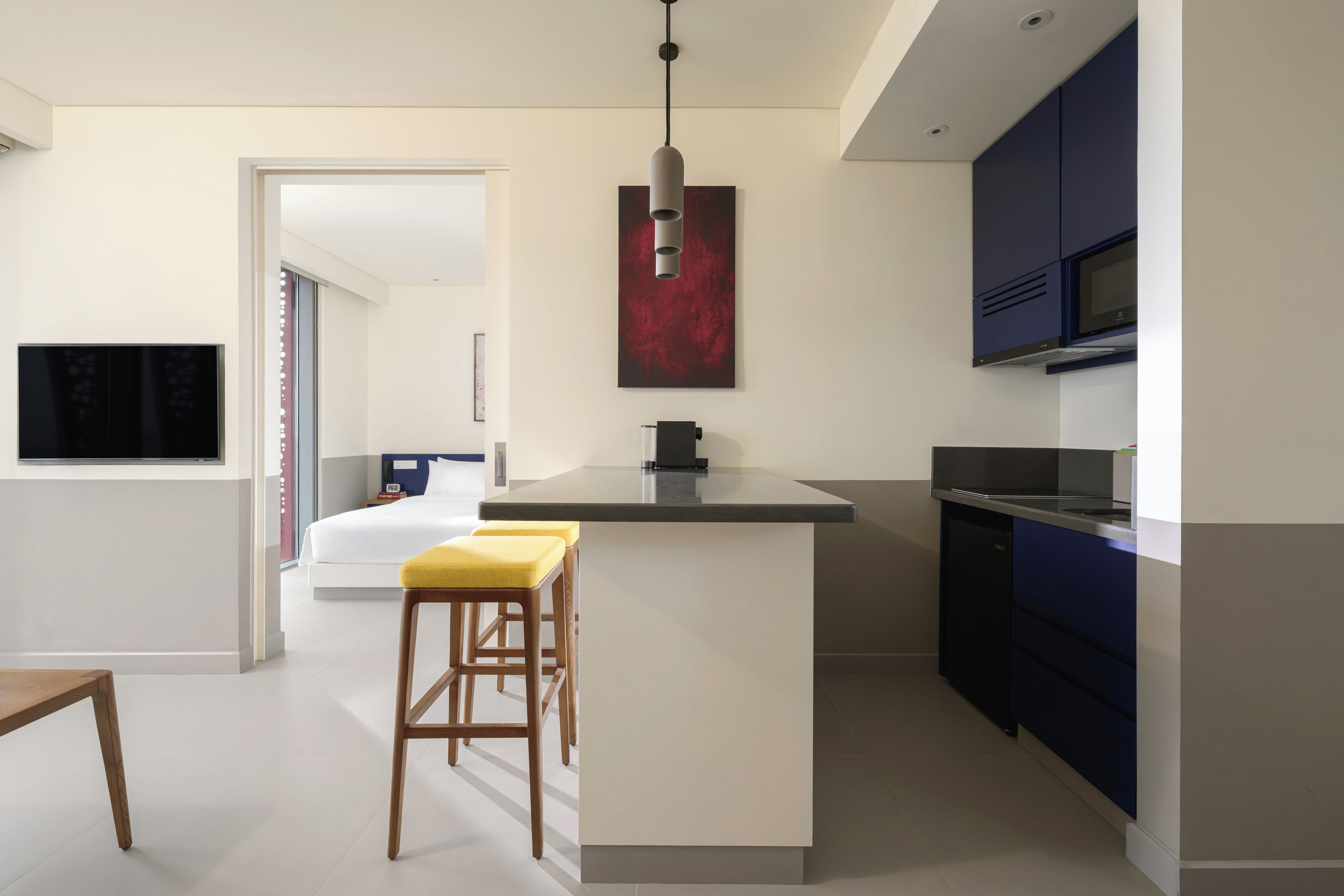 Una cocina moderna con una isla central, armarios azul oscuro y un cuadro abstracto rojo sobre la isla.