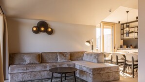 Un salon moderne avec un canapé d’angle, une table basse et un coin repas avec des chaises.