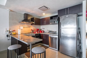Una cocina moderna con una isla central, electrodomésticos de acero inoxidable y armarios oscuros.