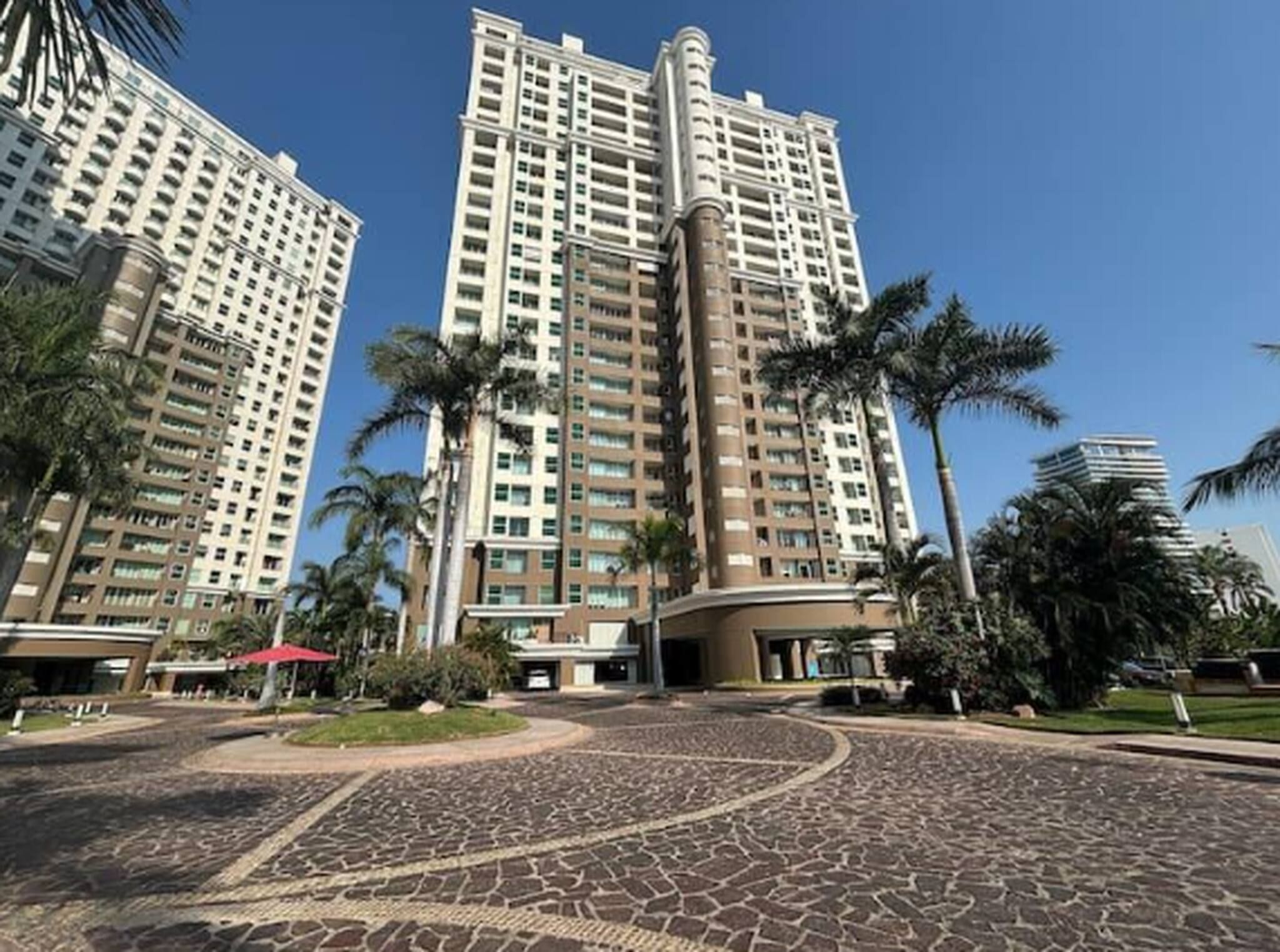 Grand high-rise buildings surrounded by majestic palm trees welcome arrivals to this tropical resort community, creating an impressive first impression with its upscale architecture and lush landscaping.