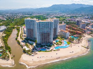 Un hôtel de grande hauteur doté de nombreux balcons, situé en bord de mer et comprenant un espace piscine.