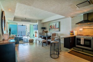 Una cocina moderna con horno Bosch, zona de comedor con taburete de bar y balcón con vistas.