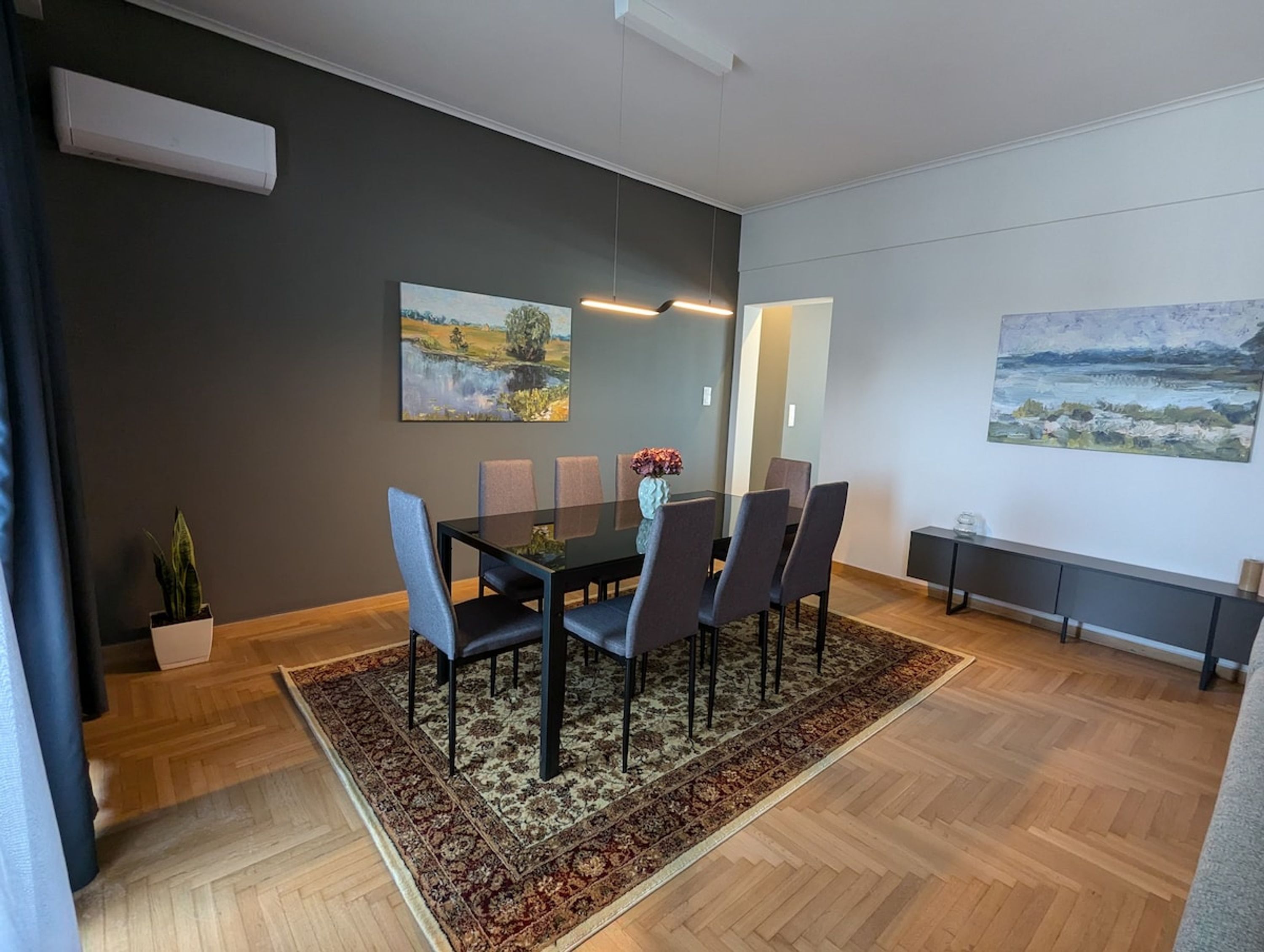 Une salle de réunion moderne avec une table en verre, des chaises sombres et un tapis à motifs.