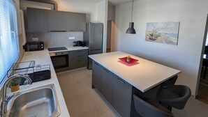 A modern kitchen with grey cabinets, a stainless steel refrigerator, a microwave, and a sink. - Spacious Seaside Flat at Alimos (Alimos)