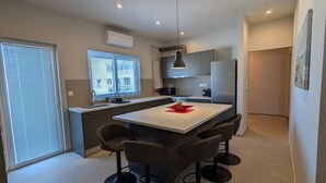 A modern kitchen with a central island, bar stools, and a refrigerator. - Spacious Seaside Flat at Alimos (Alimos)