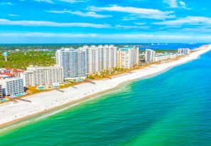 A coastal hotel with multiple high-rise buildings, a beach, and a view of the ocean.