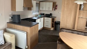 Une cuisine compacte dotée d’un îlot central, d’un coin repas avec un banc et d’un meuble intégré agrémenté d’un luminaire suspendu.