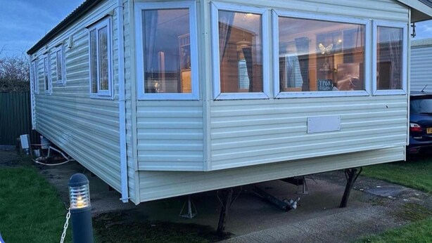 Une maison mobile dotée d’un toit plat, de grandes fenêtres et d’une porte d’entrée bien visible.