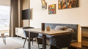 A modern living room with a dining area, a sofa, and a TV mounted on the wall.