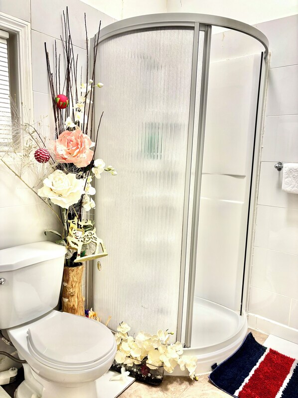 Un baño con ducha, inodoro y flores decorativas.