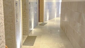 Un couloir moderne doté d’un plafond incurvé, d’un éclairage encastré et d’un mélange de revêtements muraux texturés et lisses.