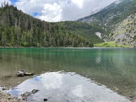 A clear lake surrounded by dense forest and mountains.