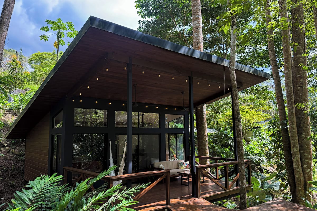 Uma cabana de madeira moderna com janelas amplas, um deck e uma rede.