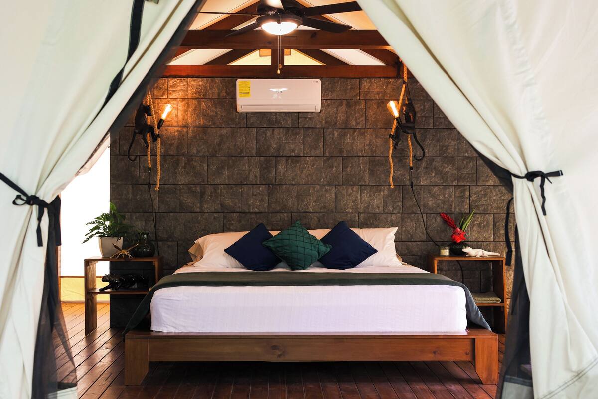 Um quarto aconchegante com uma cama de madeira, uma parede de pedra e um ventilador de teto.