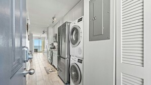 A laundry room with two front-loading washing machines, a microwave, and a refrigerator.