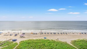 A beach with umbrellas and beach chairs, a lifeguard tower, and a fence.