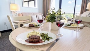 Ein Esstisch mit einem Steak, grünen Bohnen und Kartoffelpüree, dazu Weingläser.