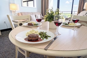 A dining table with a steak, green beans, and mashed potatoes, accompanied by wine glasses.
