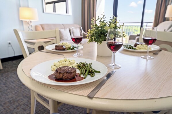 A dining table with a steak, green beans, and mashed potatoes, accompanied by wine glasses. - Grande Shores 1024-1BR- Lazy River-Myrtle Beach (Myrtle Beach)