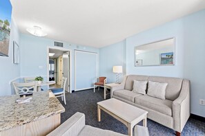 Et hotelværelse med spiseplads, en sofa, et lille bord og en lampe.